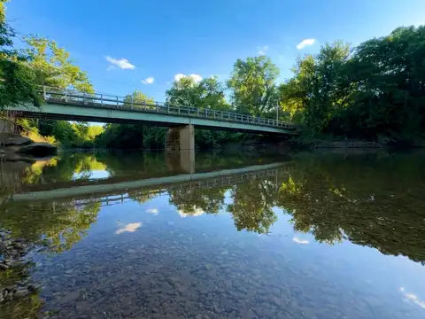 Nature's mirror: bridge, trees, and sky perfectly reflected.
